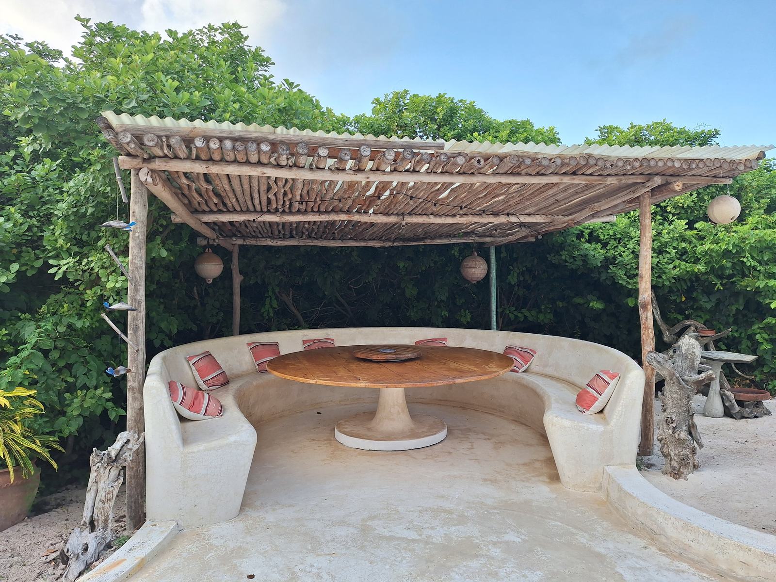 Round sunken dining banda with built-in seating under a thatched pergola