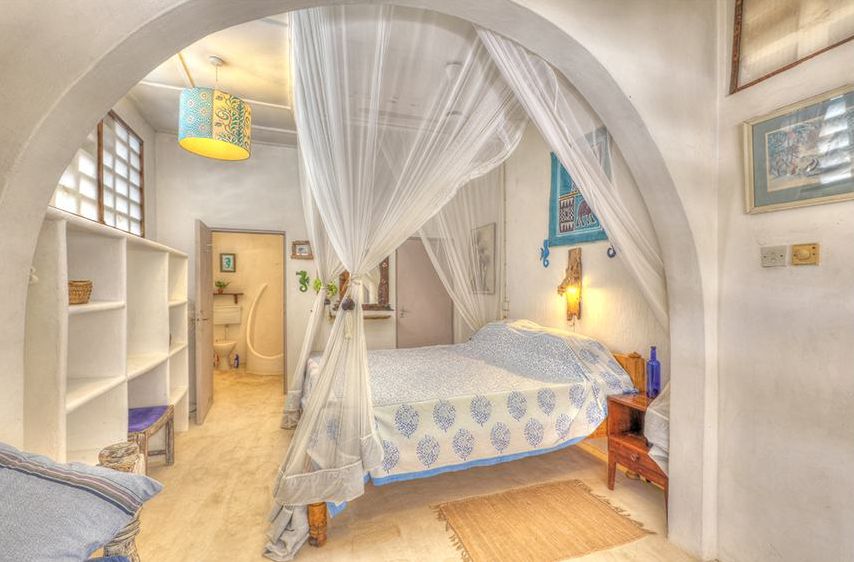 Bedroom 1 with canopy bed seen through an arch