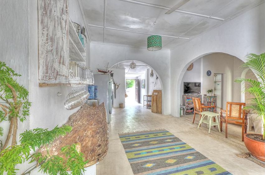 Wide white hallway with kitchen area, drinks fridge and woven rug