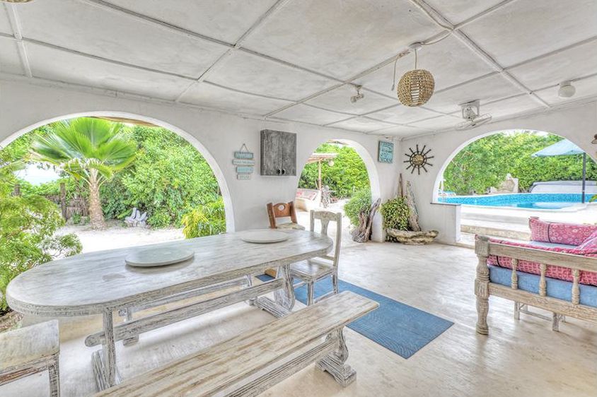 Veranda with long dining table and arched openings to the garden